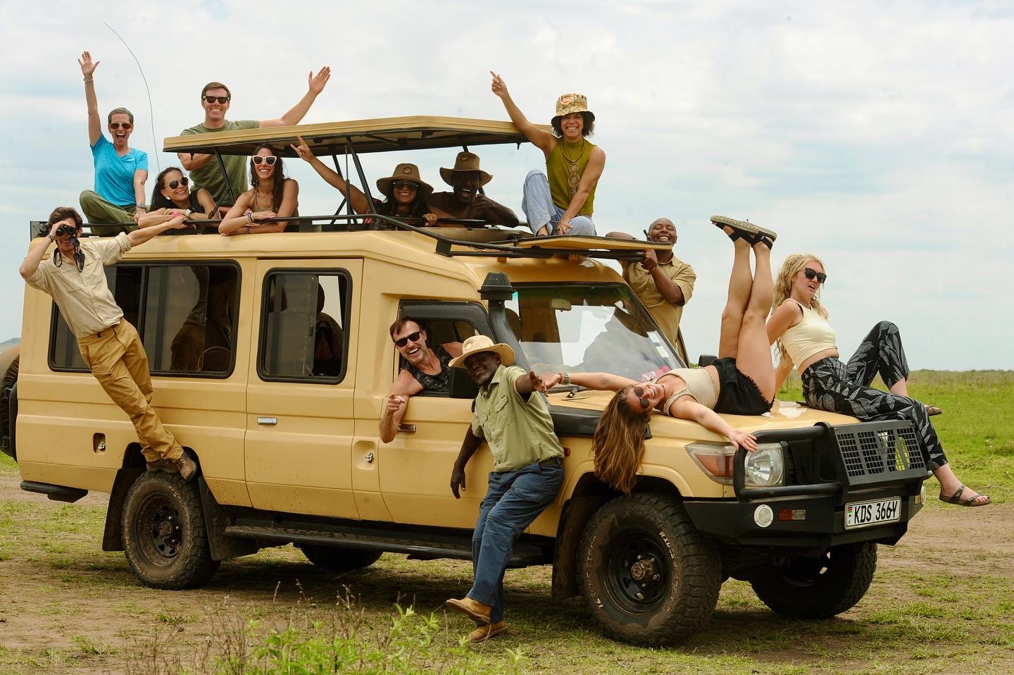 Group of travellers posing on a pop-up roof 4x4 safari vehicle