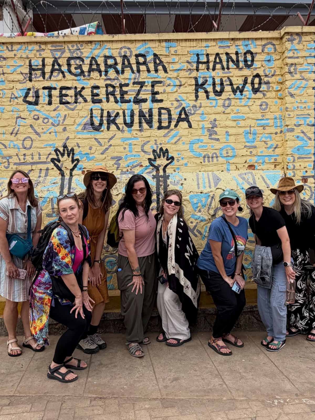 Small group of guests in front of a painted Kinyarwanda mural on a Kigali group city tour